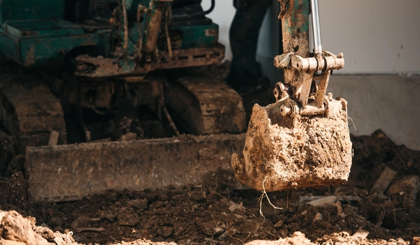 digger pulling up dirt for demolition site
